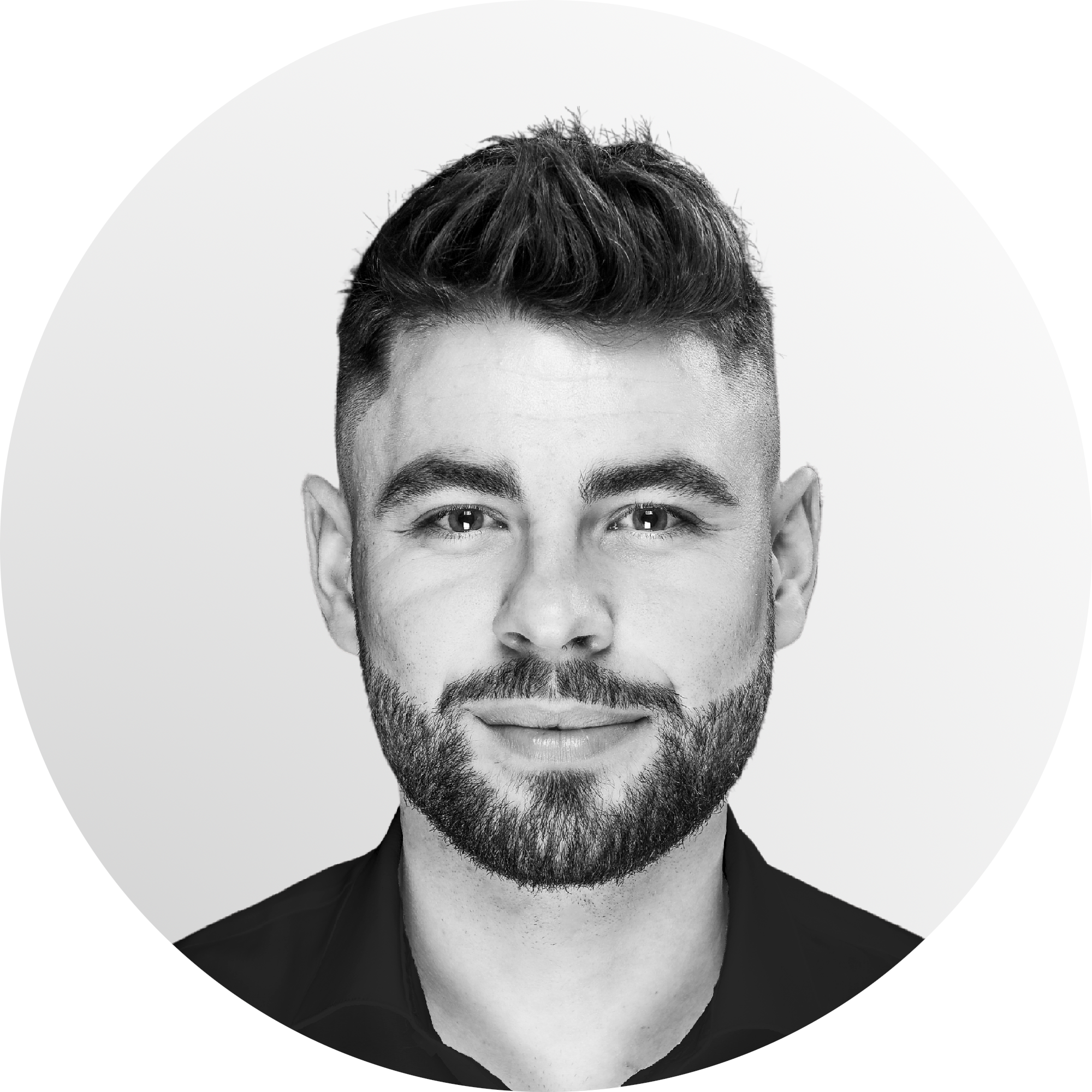 Portrait of a smiling man with a beard and styled hair, wearing a black shirt, against a white background.