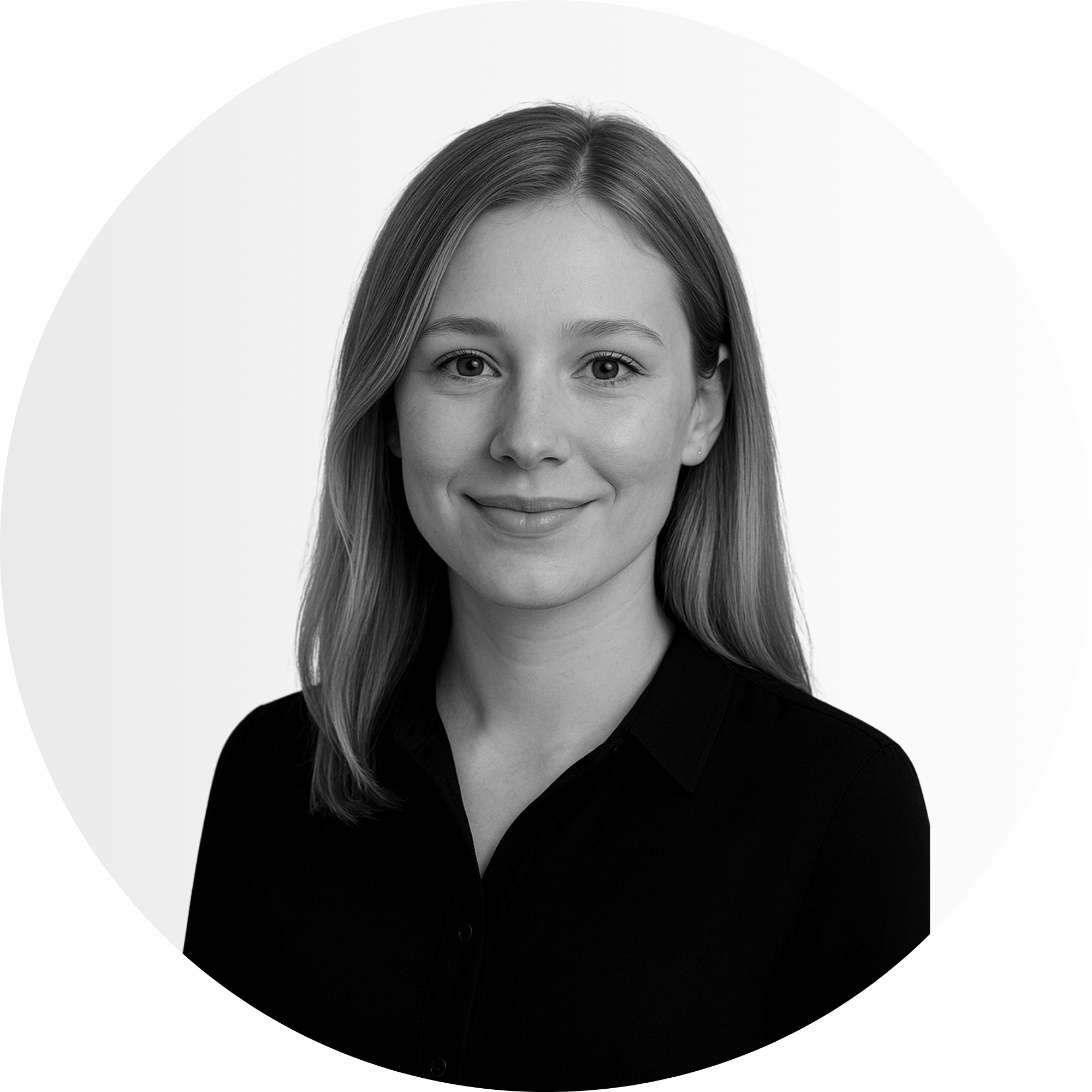 Eine Frau mit glattem, schulterlangem Haar, die ein dunkles Hemd mit Kragen trägt, nach vorne schaut und leicht lächelt, abgebildet vor einem schlichten hellen Hintergrund.